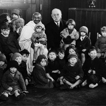 Mahatma Gandhi and George Lansbury grin as they pose with a group of children in London
